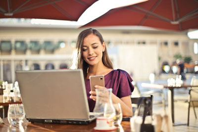 A woman on her laptop and phone, probably interested in giving online dating a try