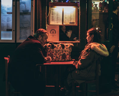 Man and woman sitting at a poorly lit corner.